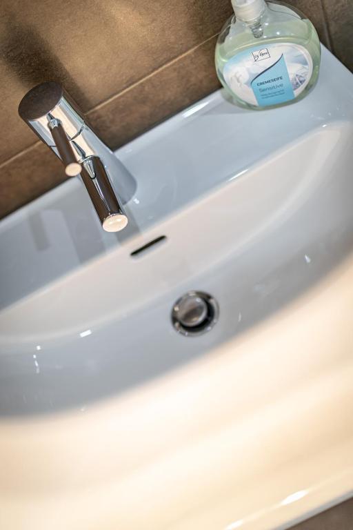 a white sink with a bottle of soap on it at Ley Apartments Vienna in Vienna