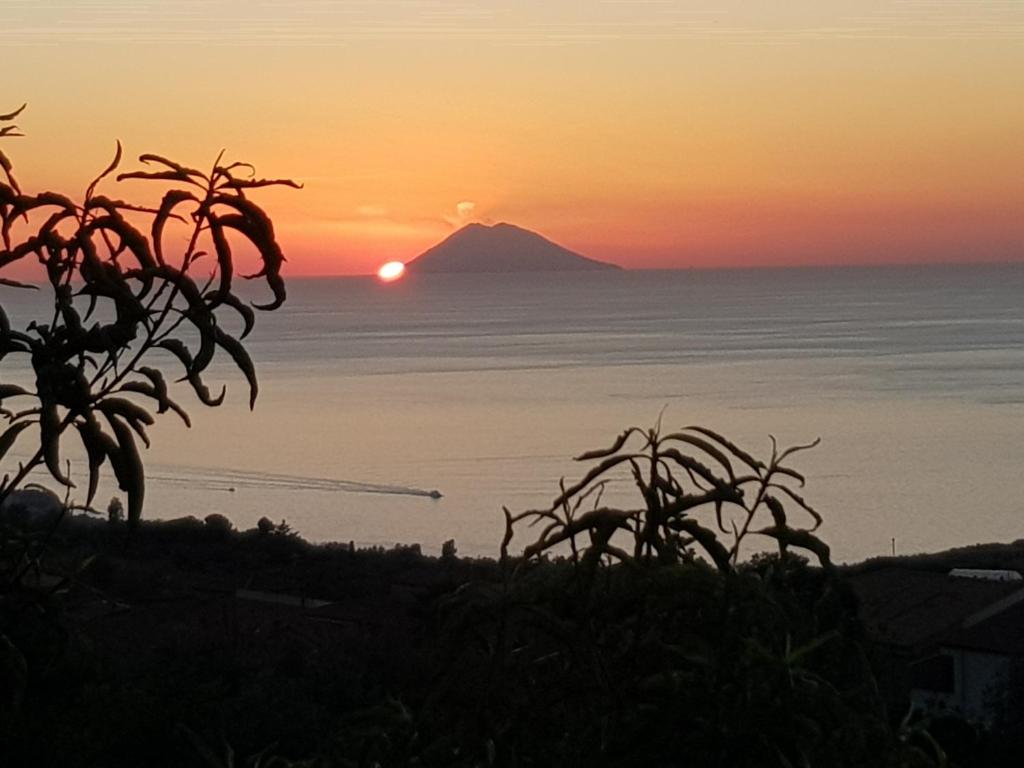 un coucher de soleil sur l'océan avec une montagne en arrière-plan dans l'établissement "la casa di Martina", à Zambrone