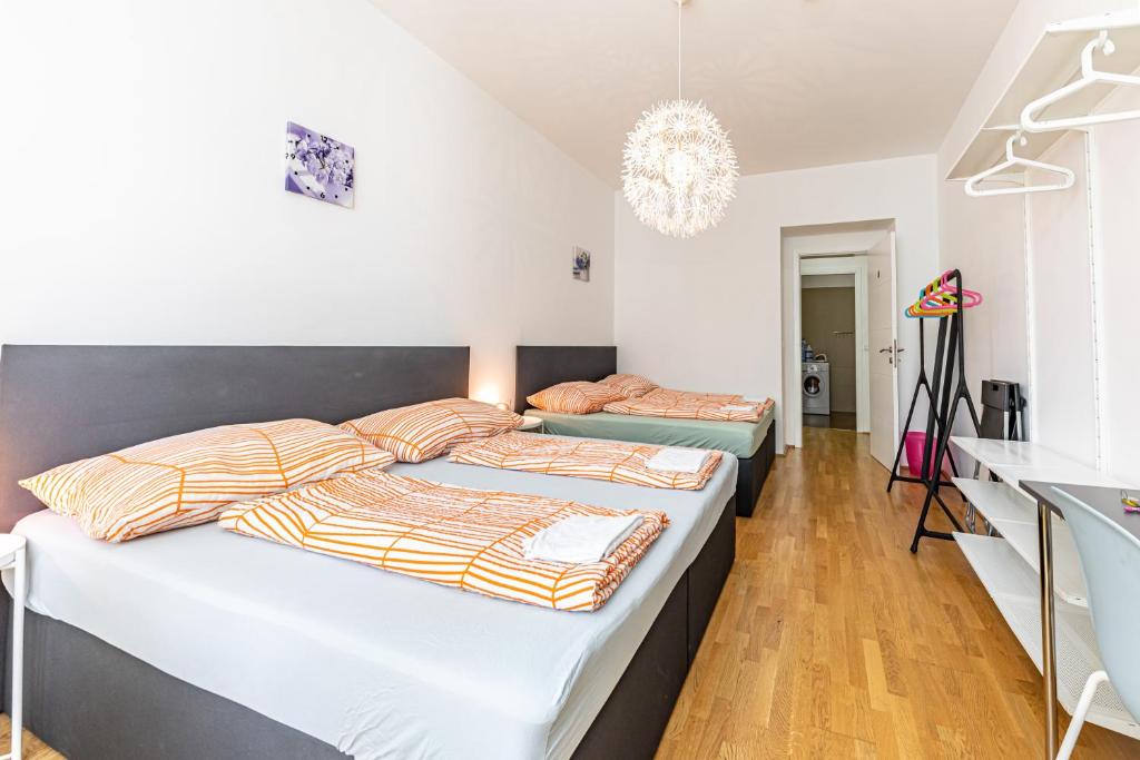 two beds in a room with white walls and wood floors at Ley Apartments Vienna in Vienna
