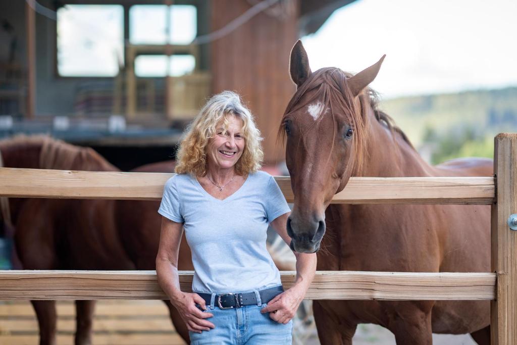 a woman standing next to a horse behind a fence at Little Graceland Ferienwohnung und Bed&Breakfast in Bonndorf im Schwarzwald