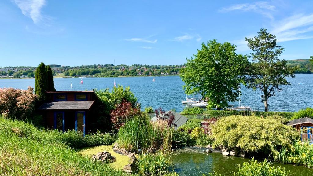 Blick auf einen See mit einem Haus und einem Garten in der Unterkunft Haus am See in Möhnesee