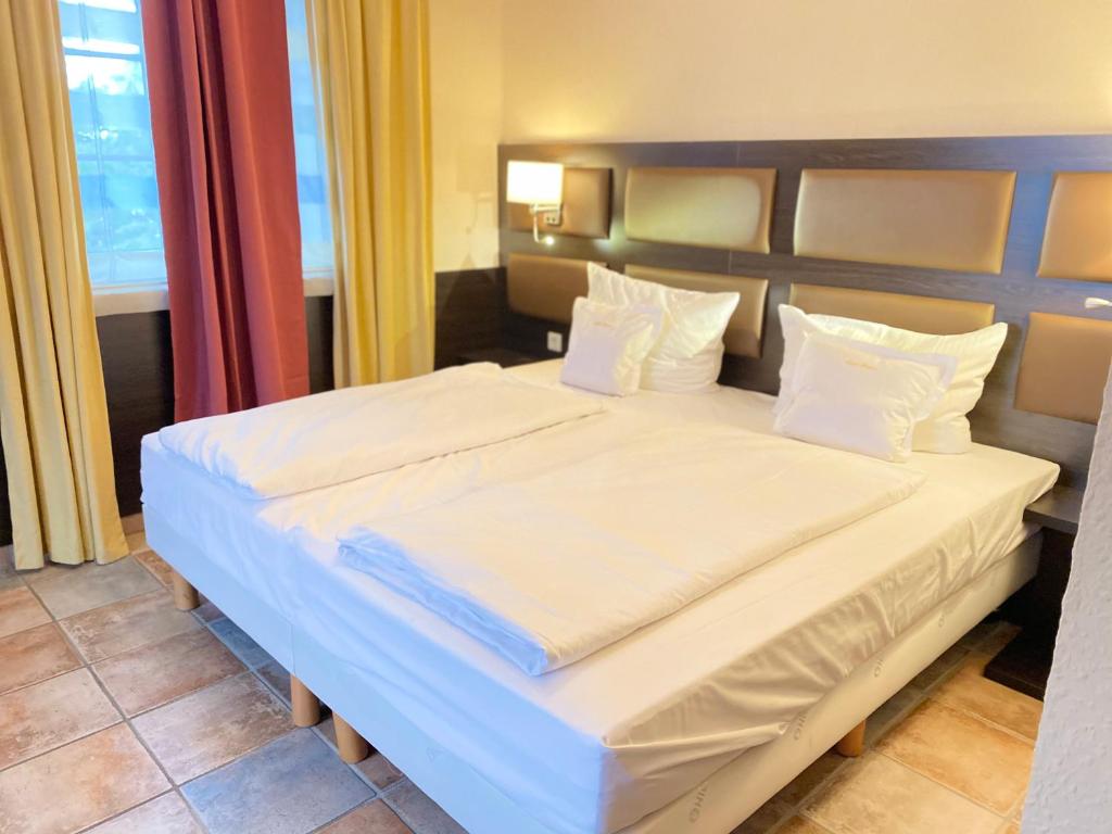 1 dormitorio con 1 cama con sábanas y almohadas blancas en Kontaktlos Hotel Vintage en Pulheim