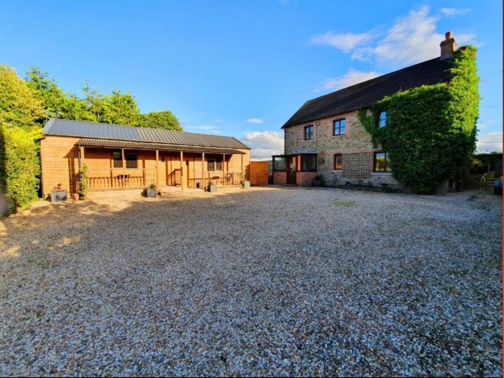 a house with a gravel driveway next to a building at Lyonshall Lodge in Kington