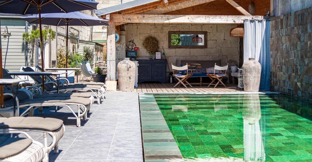 a swimming pool with chairs and umbrellas on a patio at La Marine de Loire Hôtel & Spa in Montsoreau