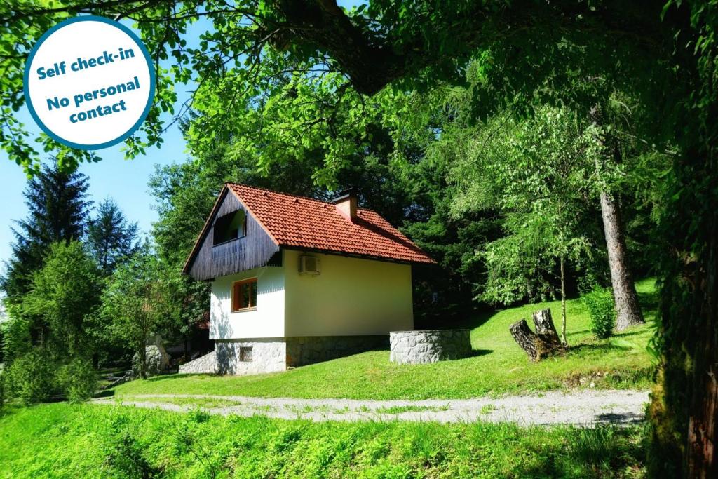 una pequeña casa en una colina con césped con una señal en Sweet Stay Forest House, en Vrhnika