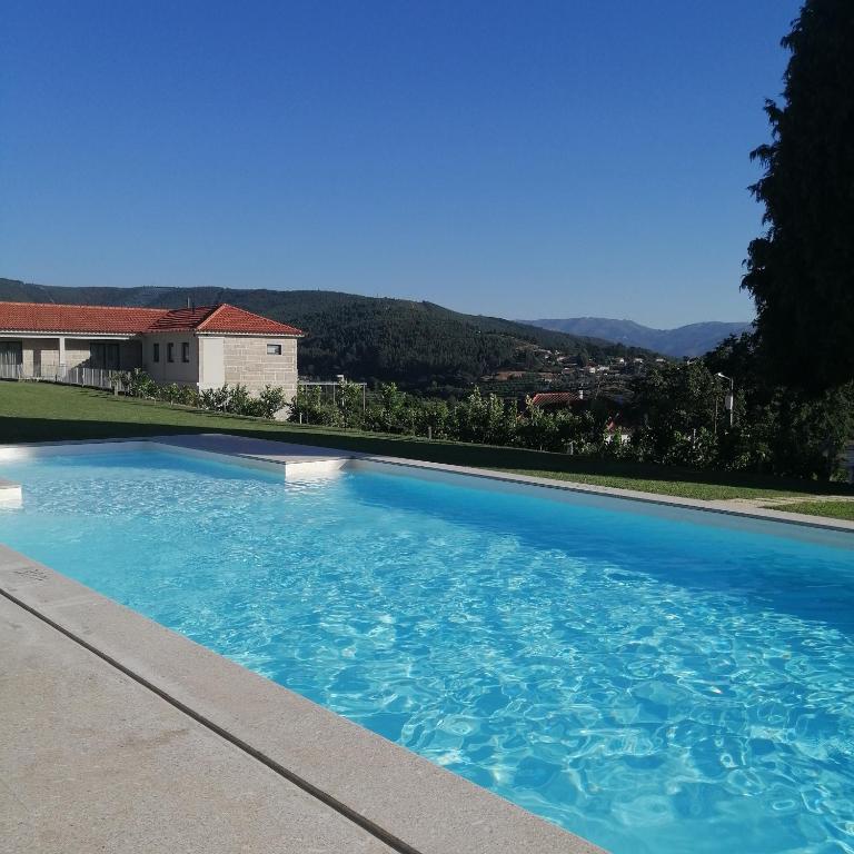a large blue swimming pool in front of a house at Casa do Soutinho in Alvarenga