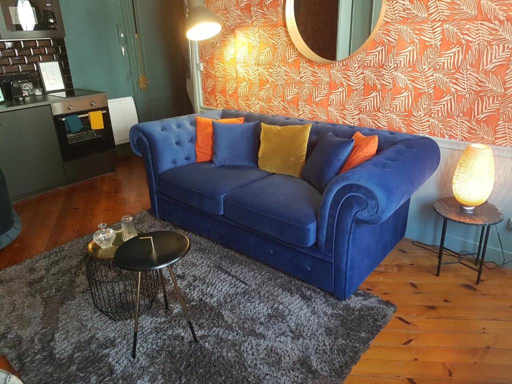 a blue couch with colorful pillows in a living room at Le repaire de Rougemare déco soignée et chaleureuse, centre historique in Rouen