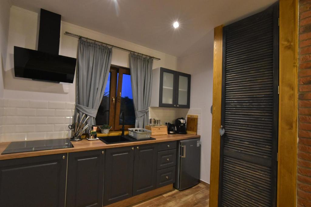 uma cozinha com armários cinzentos, uma janela e um balcão em Chatki u Oli em Baligród