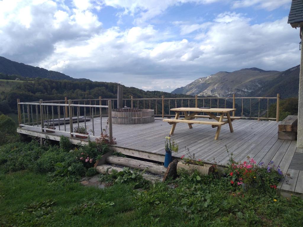 a wooden deck with a picnic table in the mountains at Le panoramique in Campan