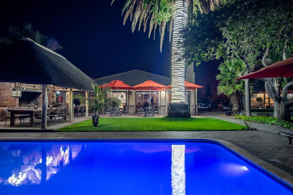 a house with a palm tree and a swimming pool at Excellent Guest House in Bellville