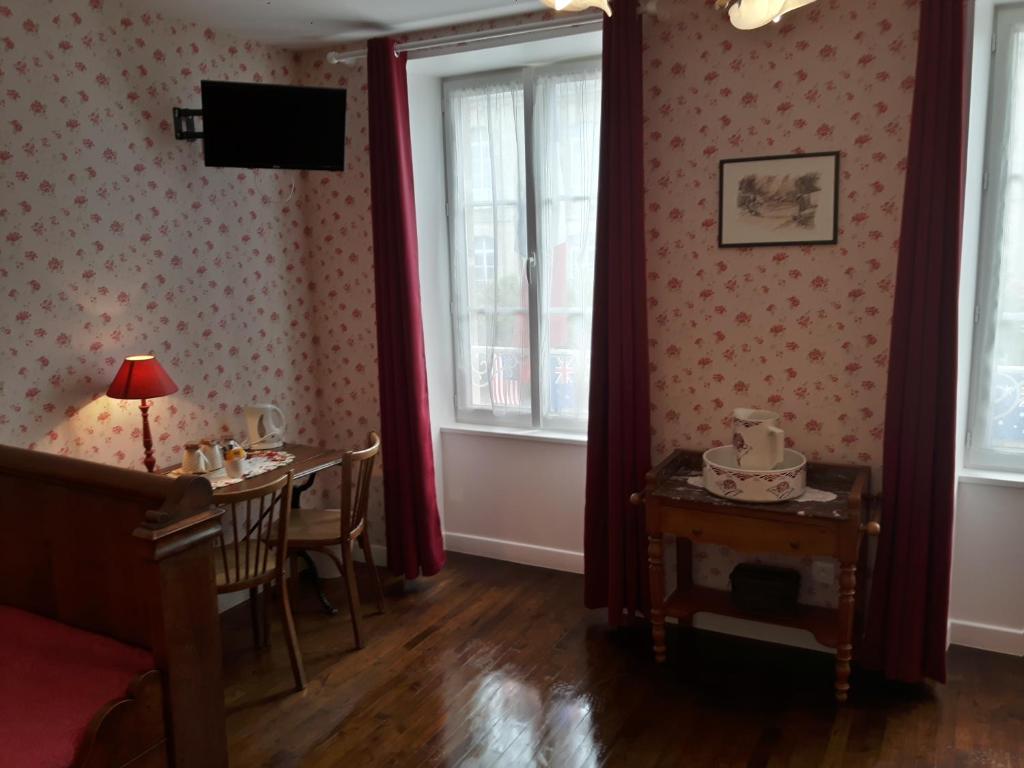 a dining room with a table and two windows at Chambres d'Hôtes et Table d'Hôtes- Valentine 44 in Sainte-Mère-Église