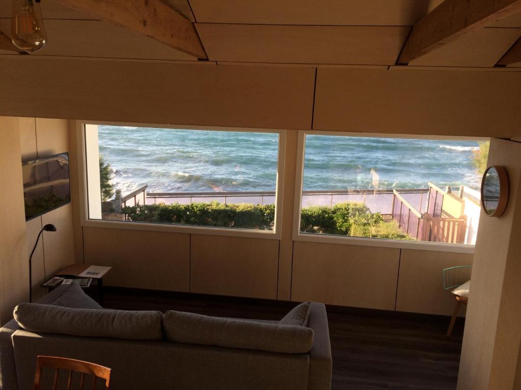 een woonkamer met 2 grote ramen met uitzicht op de oceaan bij Nouvelle Vague in Bretteville