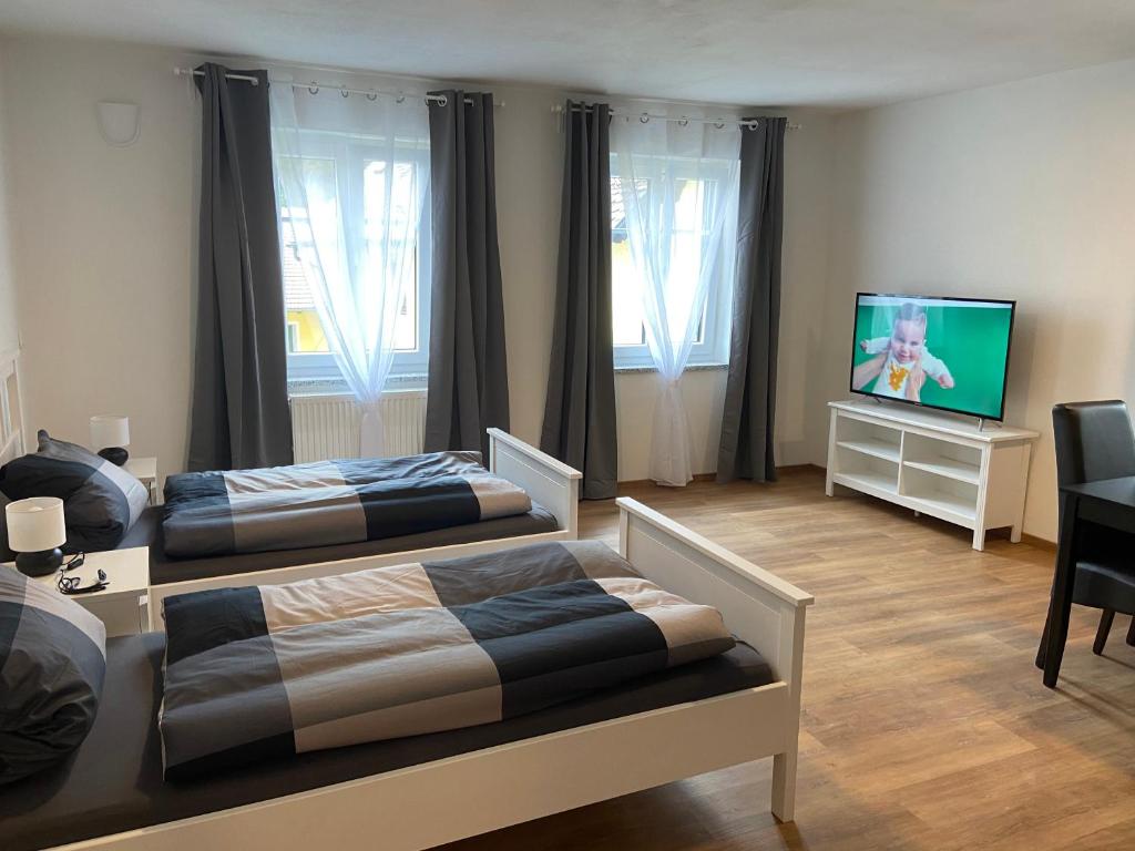 a bedroom with two beds and a flat screen tv at Appartments Siegenburg in Siegenburg