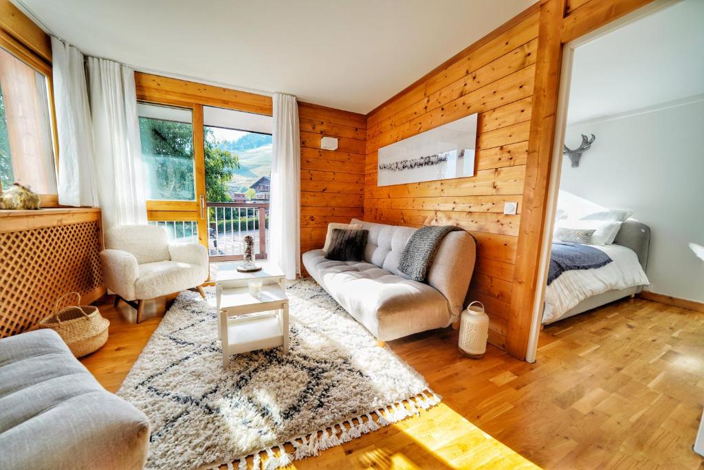 een woonkamer met een bank en een bed bij La Ménandière in Megève