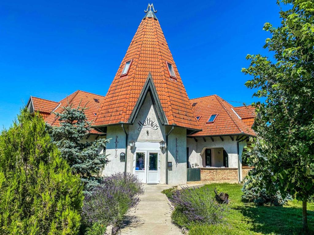 een groot huis met een oranje dak bij Mathias Ház in Magyarhertelend