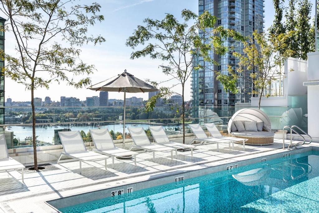 a pool with lounge chairs and an umbrella on top of a building at Level Yaletown - Richards in Vancouver