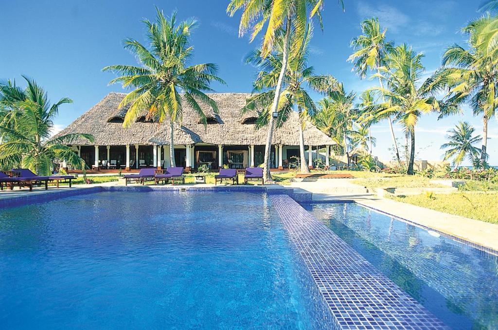 una piscina frente a una casa con palmeras en The Palms Zanzibar en Bwejuu