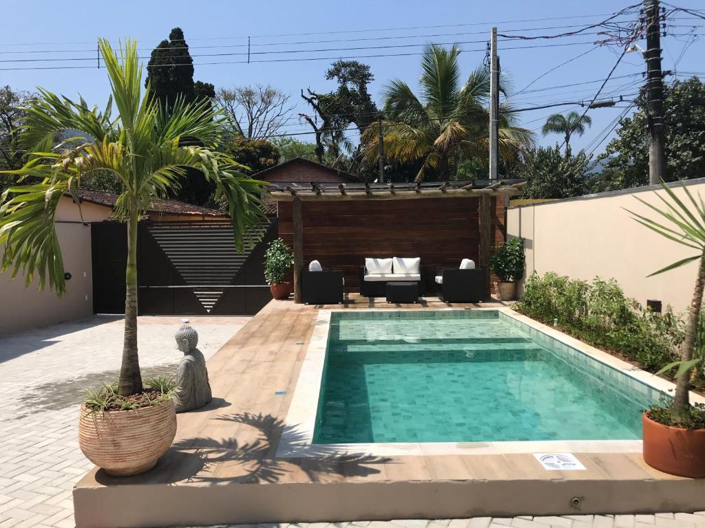 una piscina en el patio trasero de una casa con palmeras en Flats de Sumatra, en Boicucanga