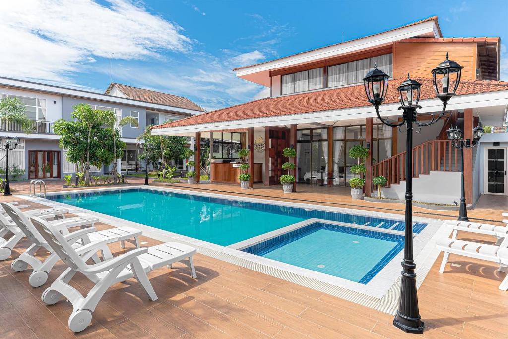 a swimming pool with chairs and a house at Sandy Residence Sihanoukville in Sihanoukville
