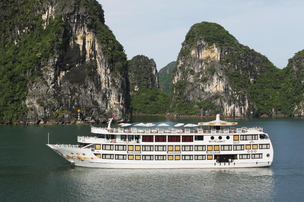 a cruise ship in the water in front of limestone cliffs at Starlight Cruise in Ha Long