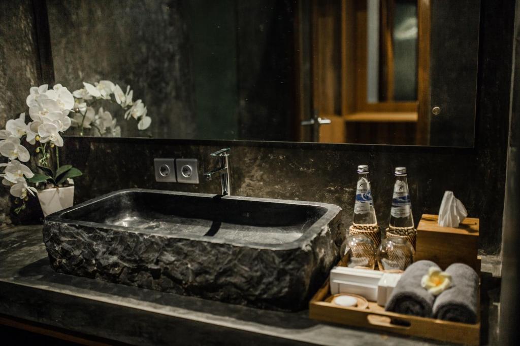 a bathroom with a stone sink and two bottles of water at Ubud Season Villas in Ubud