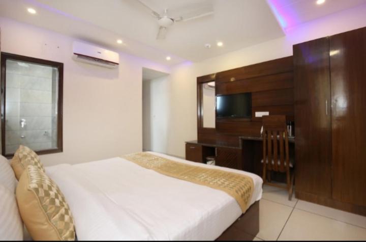 um quarto com uma cama, uma secretária e uma televisão em HOTEL SILVER PALM em Zirakpur