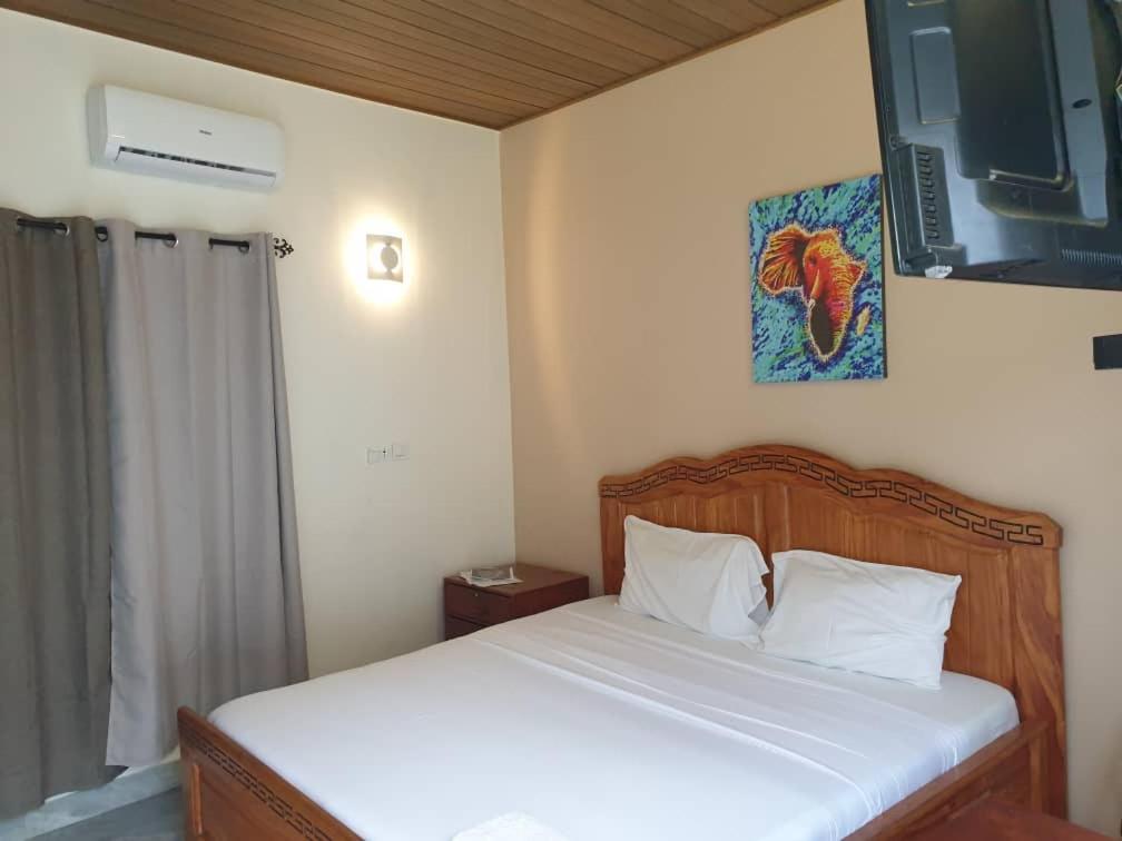 1 dormitorio con 1 cama con sábanas blancas y una foto en la pared en Residence Ivoire Cotonou, en Cotonou