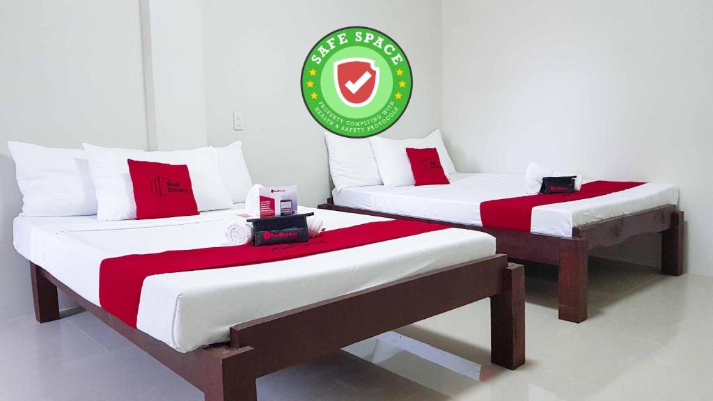 two beds in a room with a sign on it at RedDoorz @ VP Inting Street in Tagbilaran City