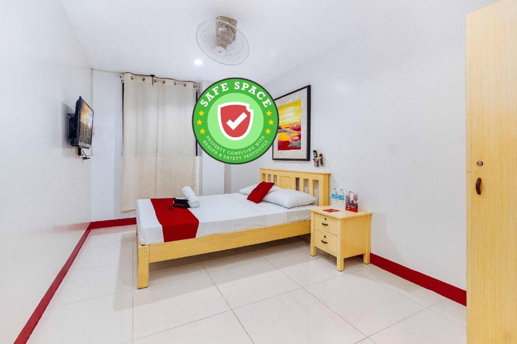 een slaapkamer met een bed en een bord aan de muur bij RedDoorz near Cebu Metropolitan Cathedral in Cebu City