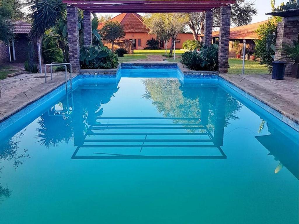 una piscina con acqua blu in un cortile di El Rancho Grande a Warmbaths