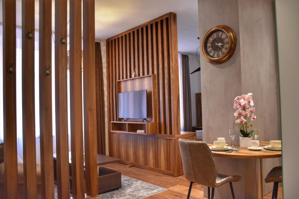 a living room with a table and a tv and a clock at Blaumana Residence Apartments in Riga