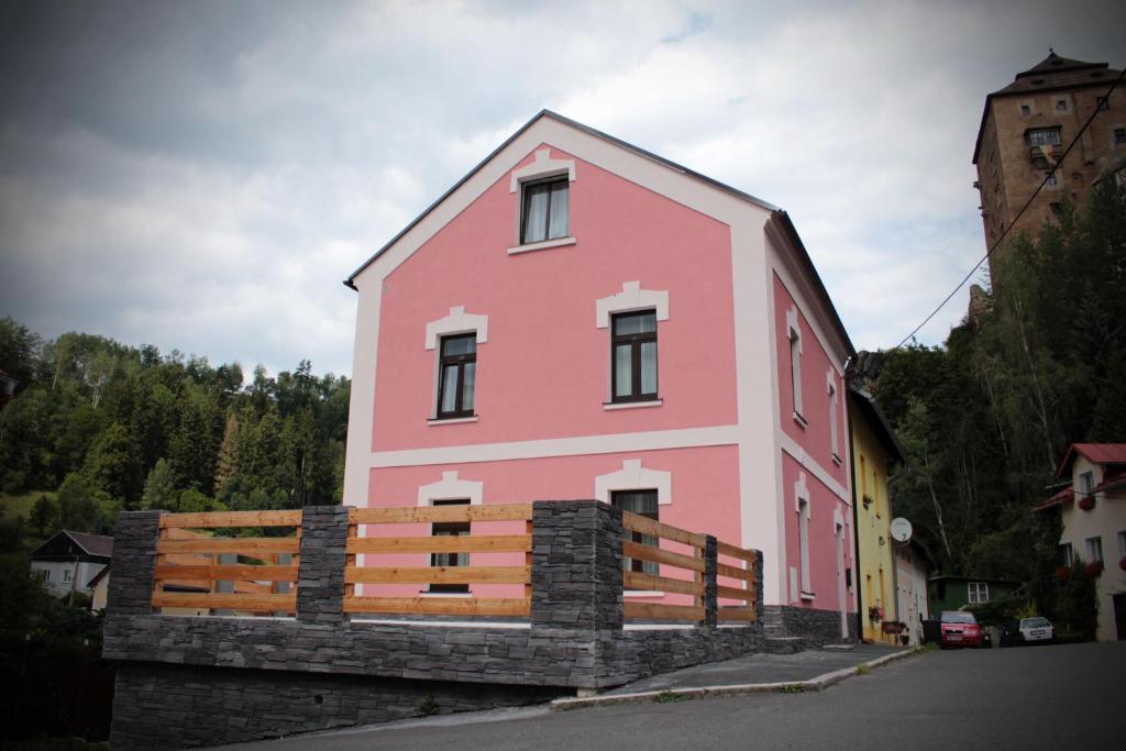 Um edifício cor-de-rosa com uma vedação à frente. em Apartmány v podhradí em Becov nad Teplou