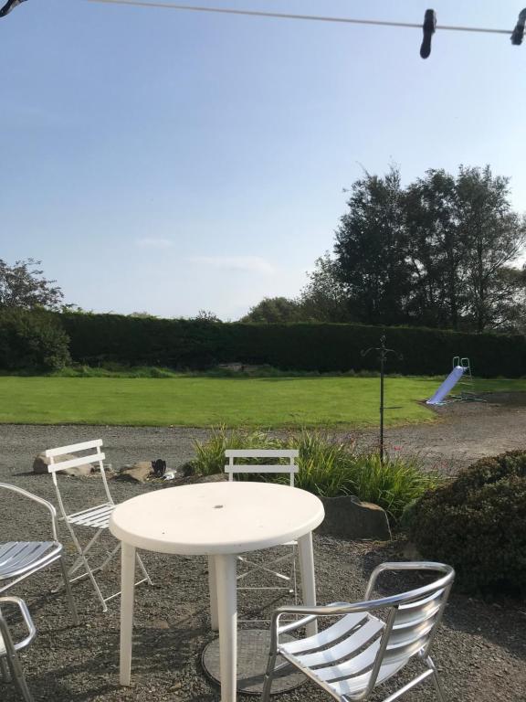 a white table and chairs with a playground in the background at Ballyginny Cottage in Maghera