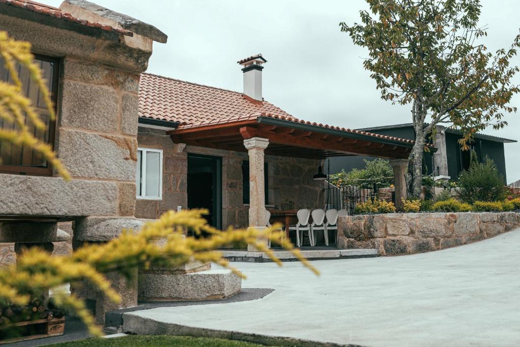une maison avec une terrasse couverte et des chaises en face de celle-ci dans l'établissement Casa da Oliveira, à Poio