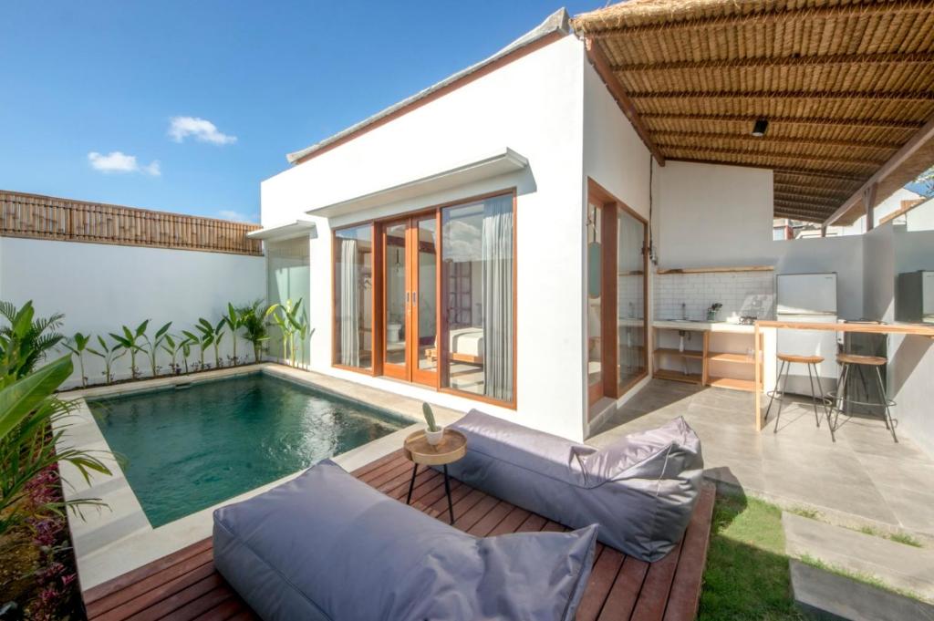a backyard with a swimming pool and a house at Kiki Village Private Villas in Canggu