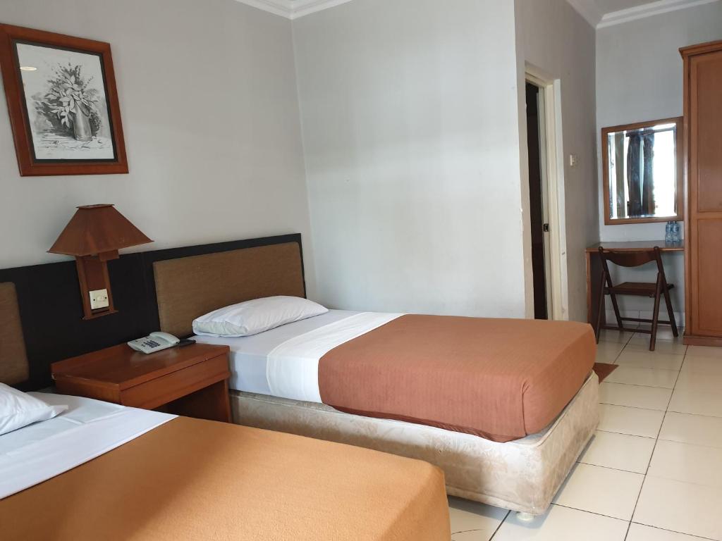 Yehezkiel Hotel Lembang Mitra RedDoorz في باندونغ: غرفة فندقية بسريرين وطاولة