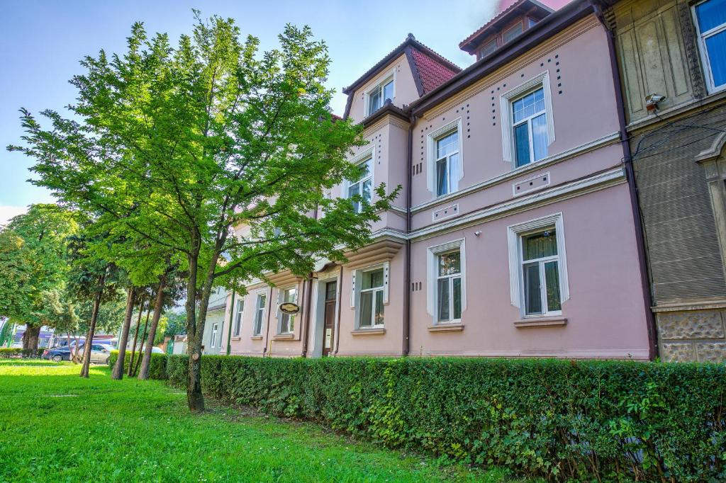 a pink building with a tree in front of it at Residence Ambient in Braşov