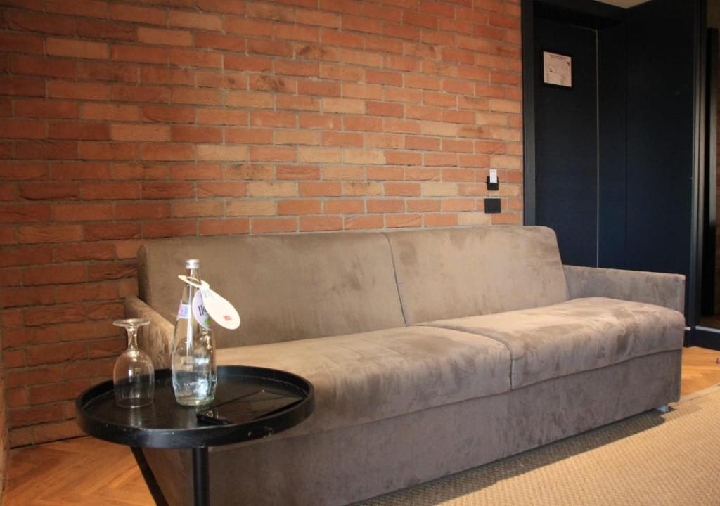a couch with a table in front of a brick wall at Caro Hotel in Bucharest