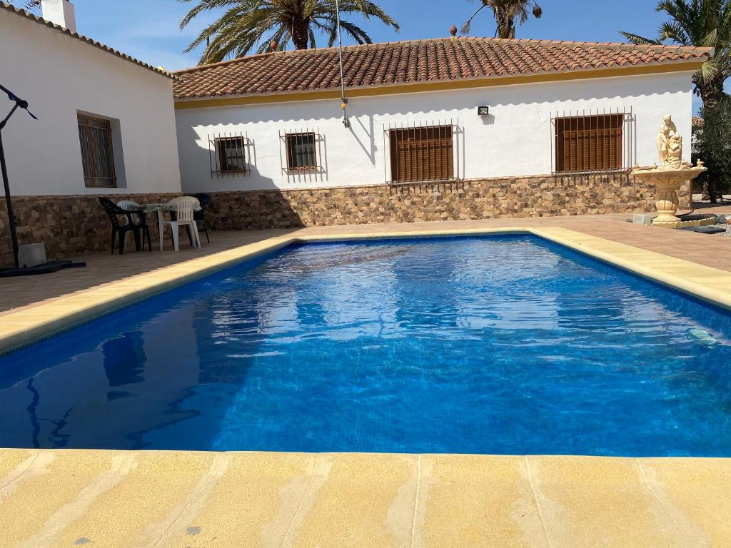 a blue swimming pool in front of a house at Chalet con piscina privada de 4 dormitorios Las Herrerias -cerca de Vera Playa- in Cuevas del Almanzora