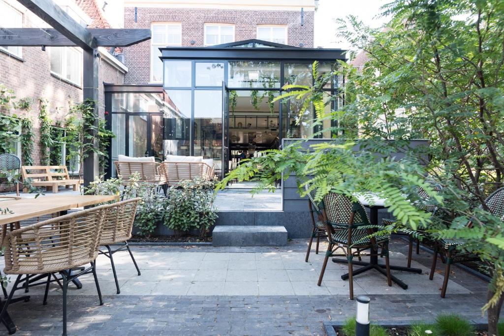 een patio met stoelen en tafels en een glazen gebouw bij Ysbrantsz Boutique Hotel in Hoorn