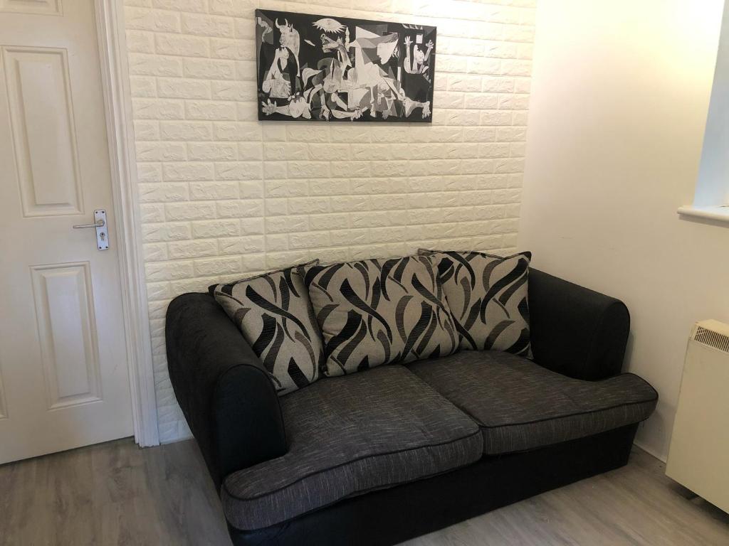 a couch sitting in a living room next to a wall at Double Room with Private Bathroom in a 2-bedrooms house in London