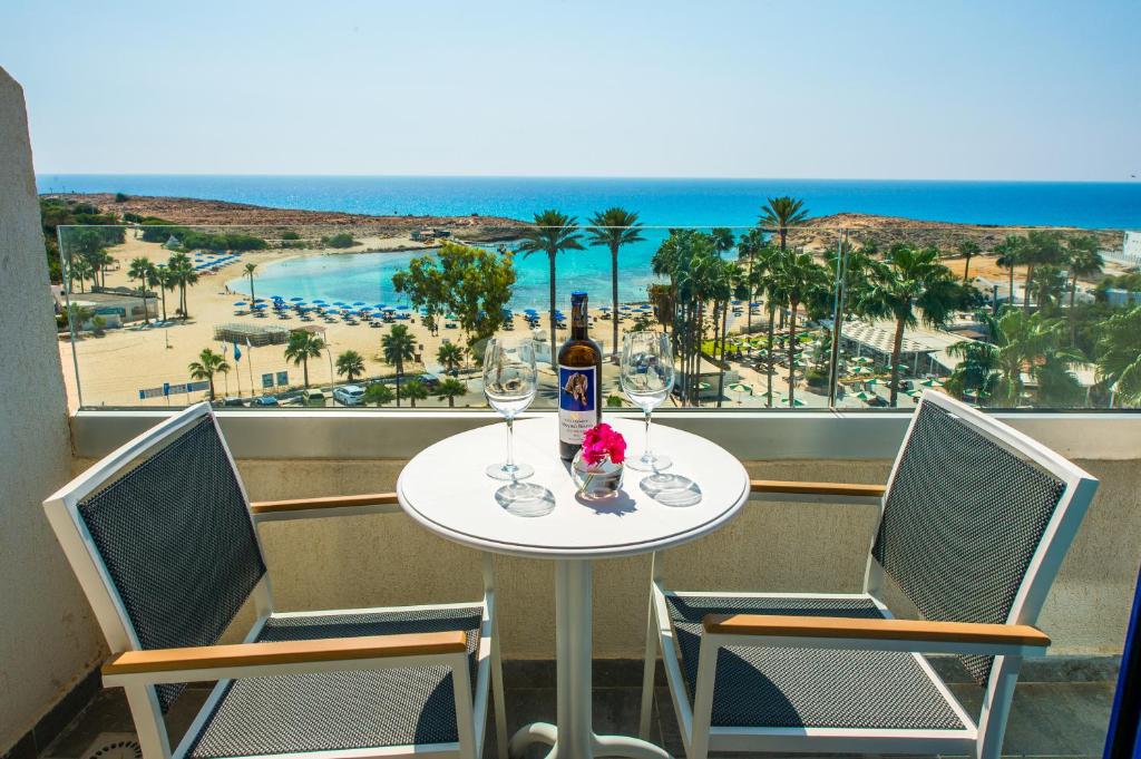 a table with a bottle of wine and two chairs at Anonymous Beach Hotel (Adults 16+) in Ayia Napa