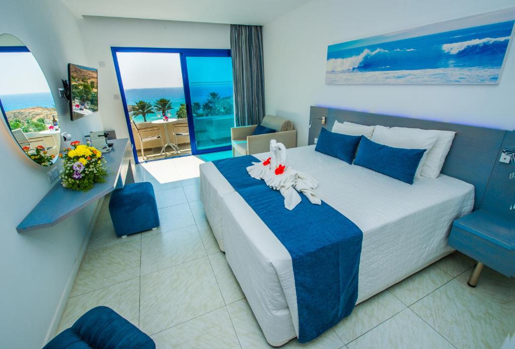 a bedroom with a large bed with a blue blanket at Anonymous Beach Hotel (Adults 16+) in Ayia Napa