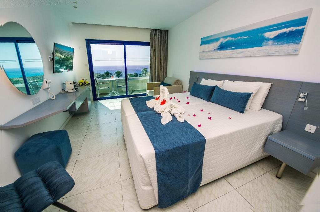 a bedroom with a large bed and a desk and chairs at Anonymous Beach Hotel (Adults 16+) in Ayia Napa