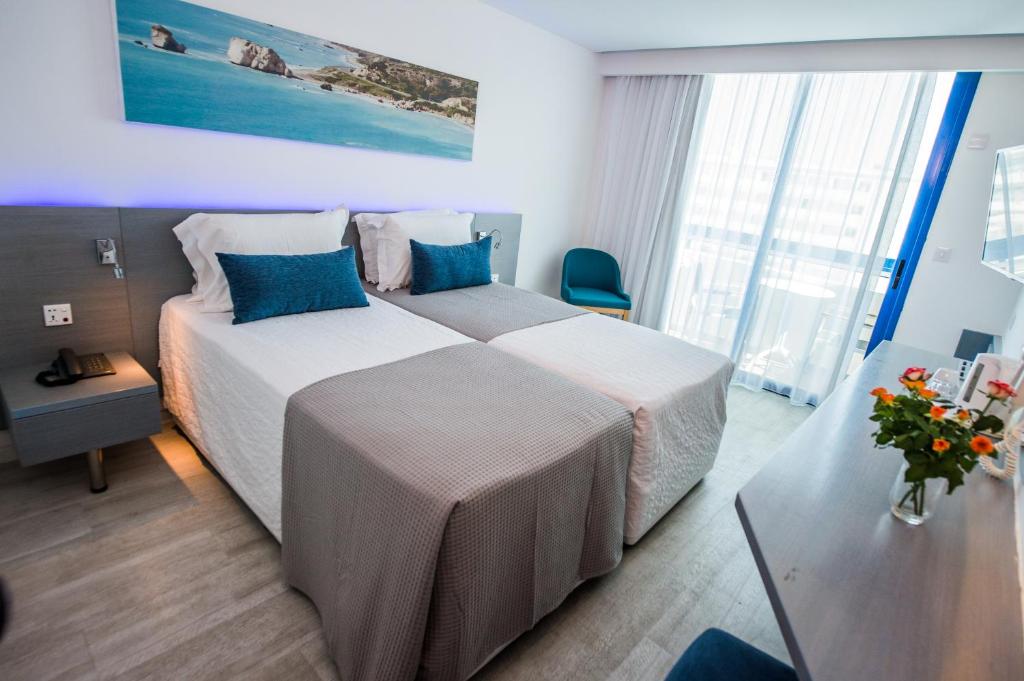 a hotel room with two beds with blue pillows at Anonymous Beach Hotel (Adults 16+) in Ayia Napa