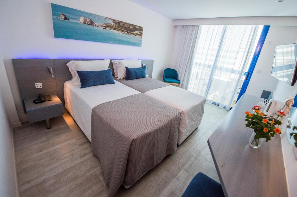 a hotel room with two beds and a table at Anonymous Beach Hotel (Adults 16+) in Ayia Napa