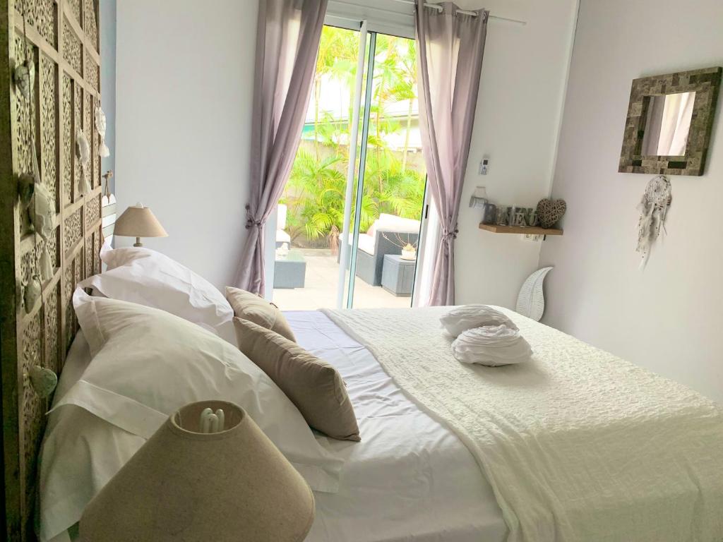 Cama blanca en habitación con ventana en la maison du bonheur, en Saint-Pierre