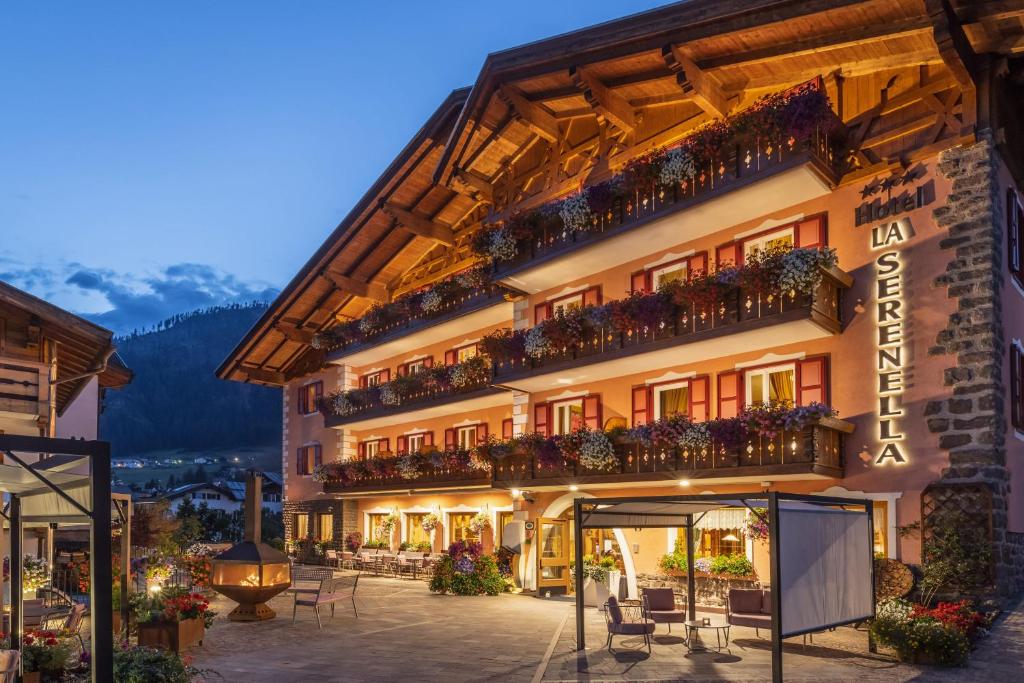 un hôtel avec des tables et des chaises devant lui dans l'établissement Hotel La Serenella, à Moena