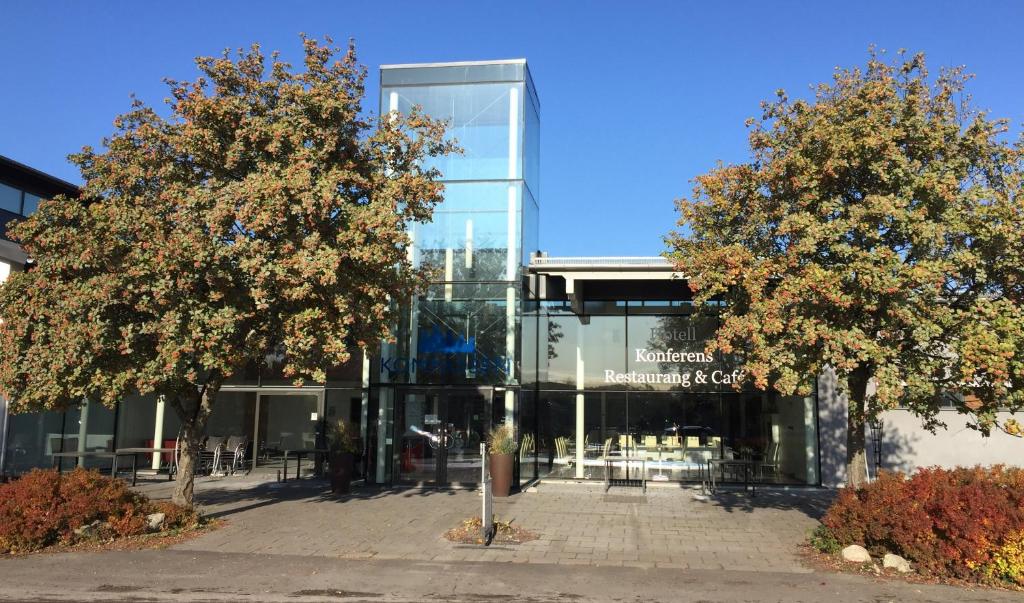 un bâtiment en verre avec deux arbres devant lui dans l'établissement Kompassen, à Enköping