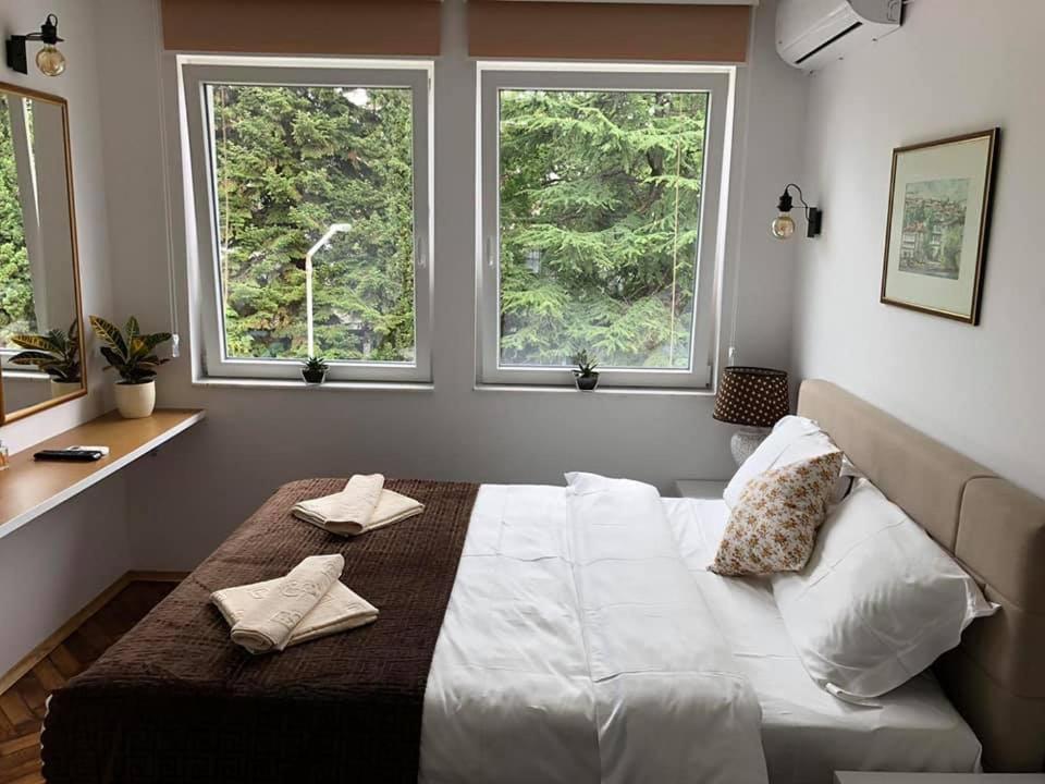 a bedroom with a large white bed with two windows at Labroski Apartments in Ohrid